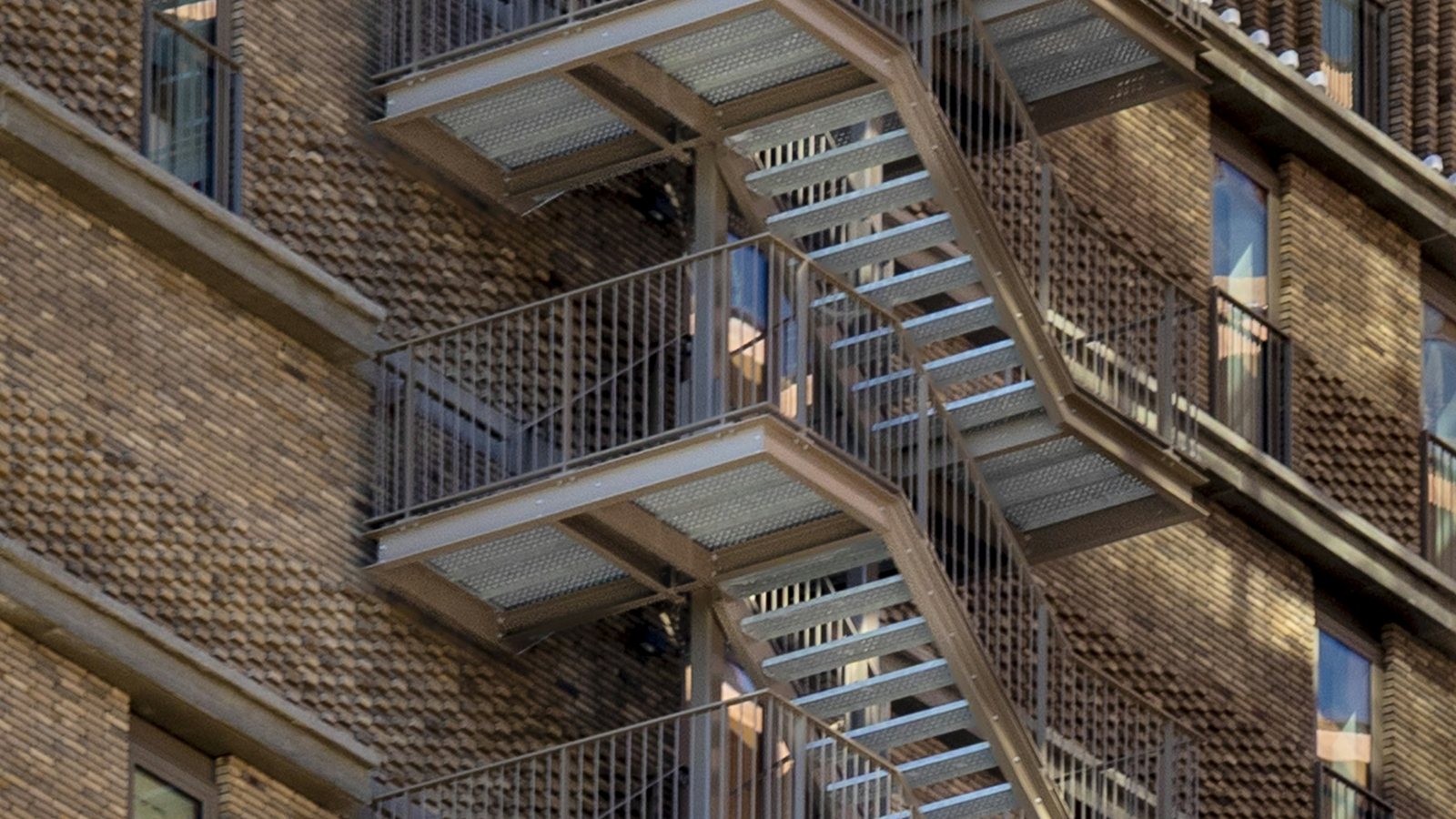Escadas metálicas de emergência em ziguezague na lateral de um edifício antigo de tijolos