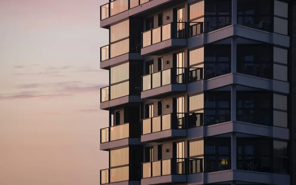 Fachada de edifício residencial com sacadas envidraçadas ao entardecer