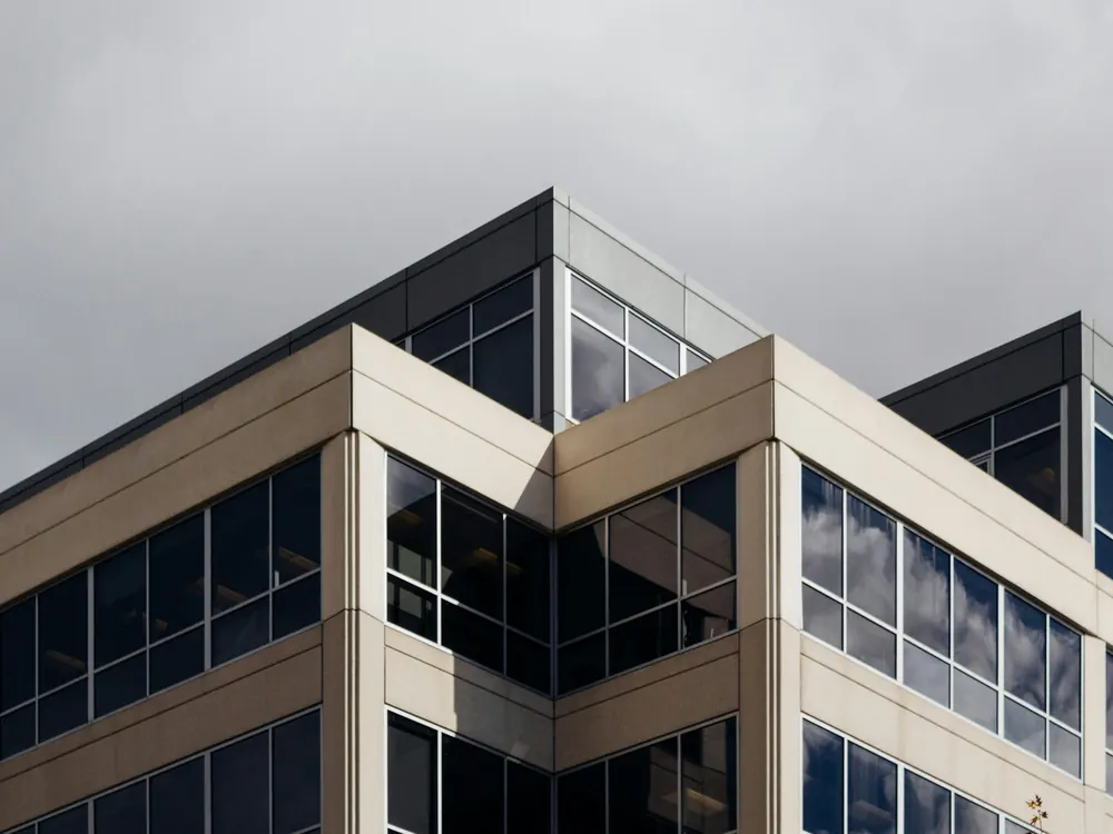 Esquina de edifício comercial com fachada bege e caixilhos de vidro