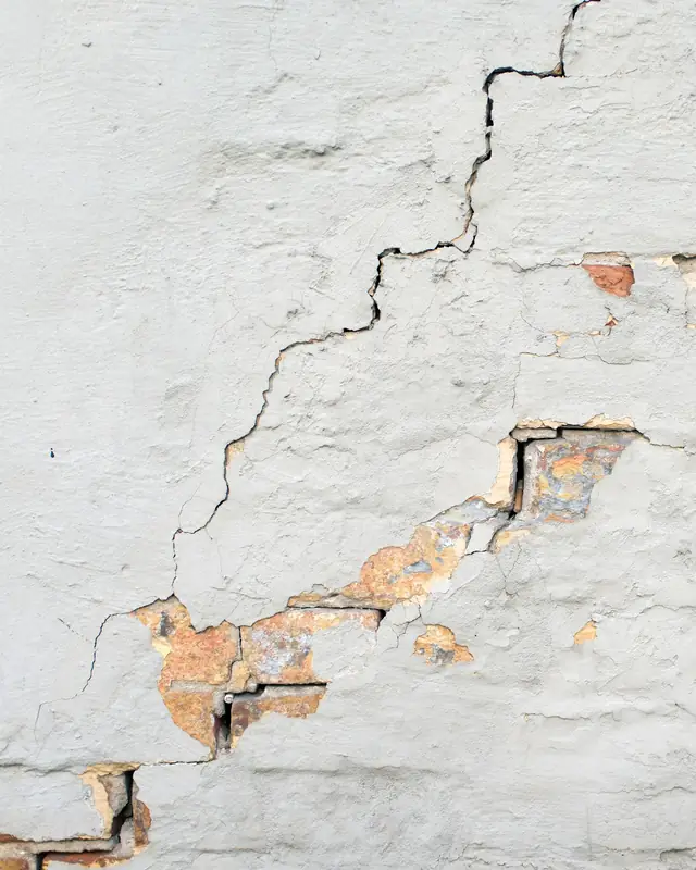 Trinca em escada numa parede de alvenaria pintada, com trechos de tijolo aparente