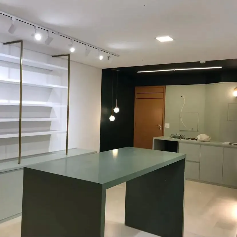 Ambiente interno com parede em verde profundo, trilho de iluminação, pendentes e marcenaria após pintura e acabamento