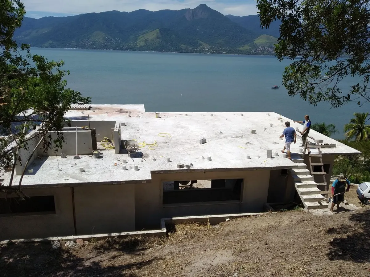 Laje concretada da residência com escada lateral de acesso, o mar e a serra ao fundo