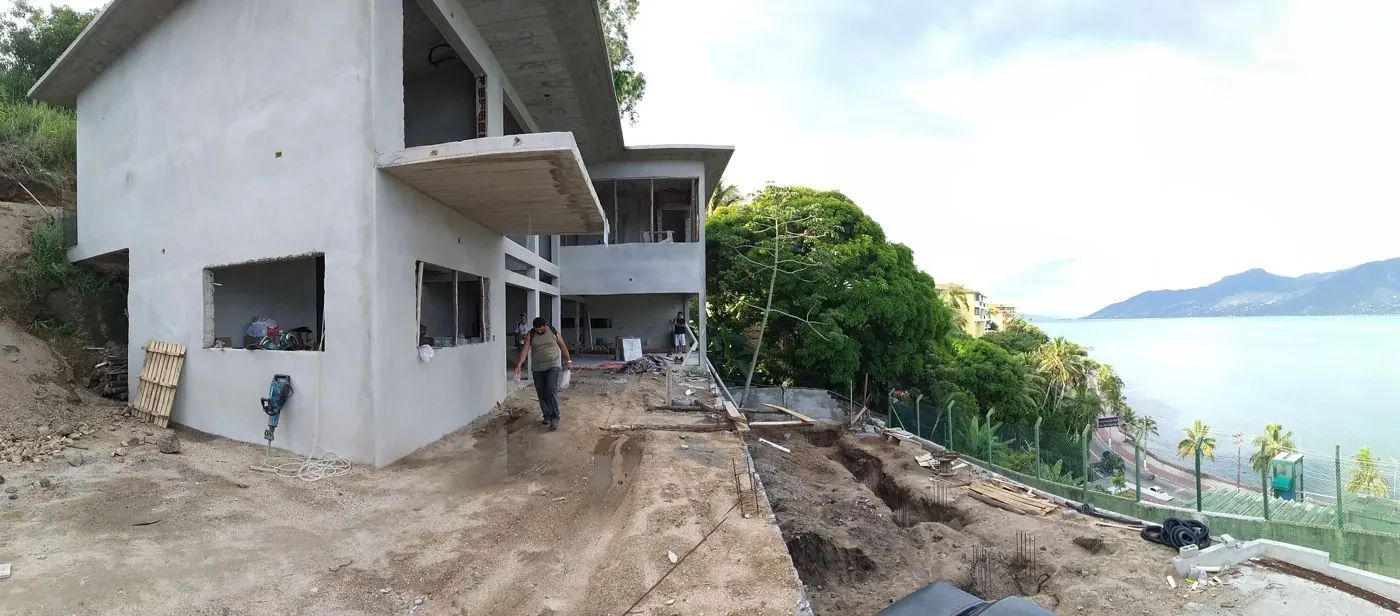 Volumes da residência em estrutura vistos do acesso, com o mar ao fundo